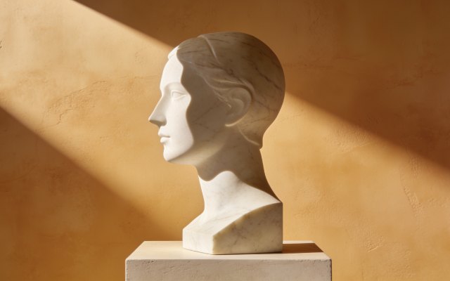 Marble sculptural profile on a plinth against warm ochre