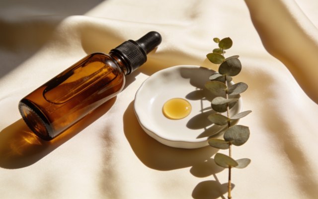 Amber dropper bottle and serum droplet on cream silk