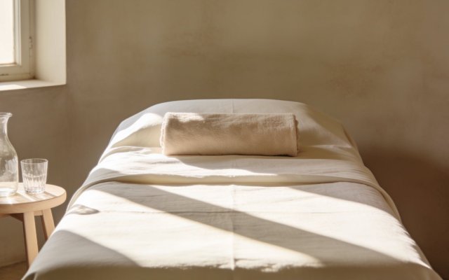 The head of a treatment bed in crisp cream linen with a water carafe